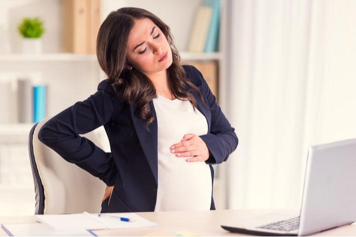 אישה בשבוע 20 להריון סובלת מכאבי גב בזמן ישיבה מול המחשב