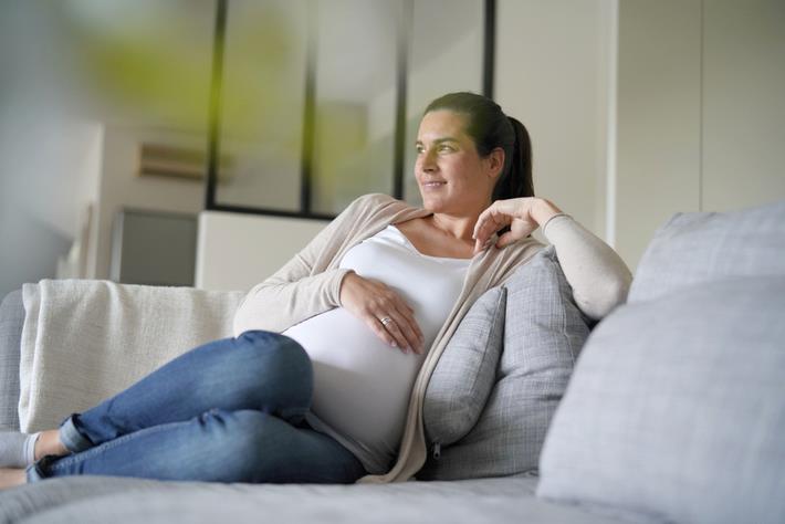 אישה בהריון בגיל 35 יושבת על ספה