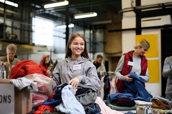 צעירה עוזרת באריזת בגדים. התנדבות בזמן מלחמה