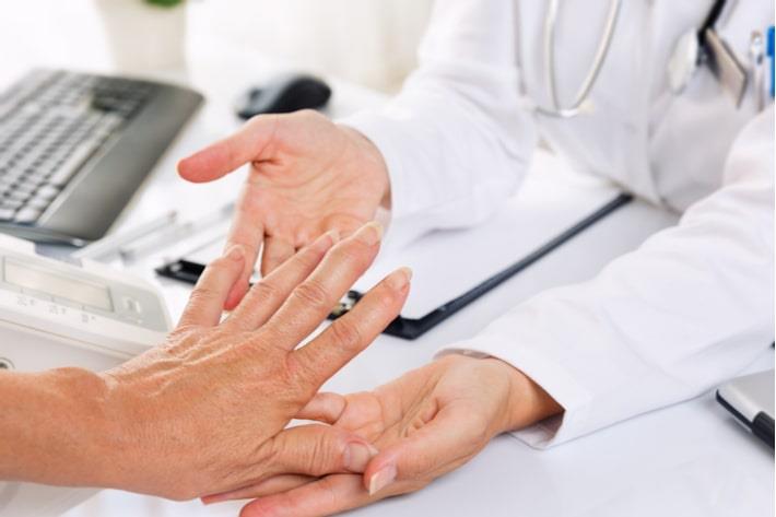 ראומטולוגית בודקת את ידה של אישה עם דלקת מפרקים שגרונית