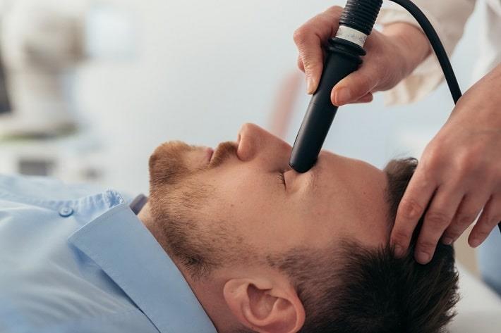 רופאה מבצעת בדיקת אולטרסאונד עיניים בגבר שוכב