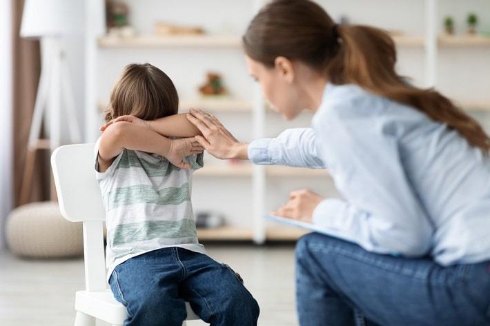 פסיכולוגית ילדים מנסה להרגיע ילד מפוחד, טיפול בחרדה בילדים