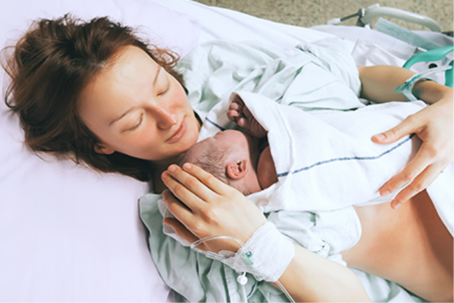 אישה מחבקת את התינוק רגע אחרי לידה