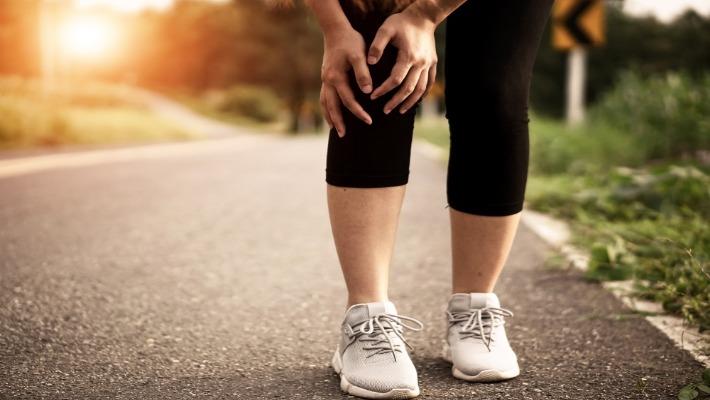 אישה צעירה אחרי פעילות ספורטיבית סובלת מכאב בברך הנובע מקרע במיניסקוס