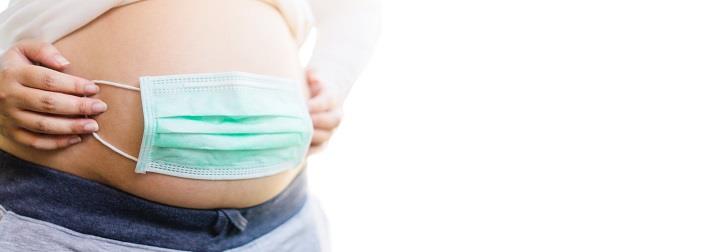 אישה בהריון מכסה את הבטן במסכה כירורגית, מדמה הגנה על העובר מפני הידבקות בנגיף הקורונה