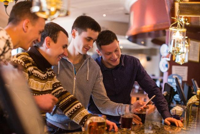 קבוצת חברים שותים אלכוהול בבר ובוחנים אפליקציה המנטרת את צריכת האלכוהול ומשמשת כתחליף למחשבון צריכת אלכוהול