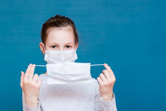 ילדה קטנה עוטה שתי מסכות כדי להתגונן טוב יותר מפני הקורונה 