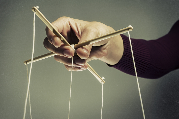 אדם מחזיק בחוטים של בובת מריונטה. אילוסטרציה לאדם שעושה גזלייטינג בנסיון לשלוט בחייו של אחר 
