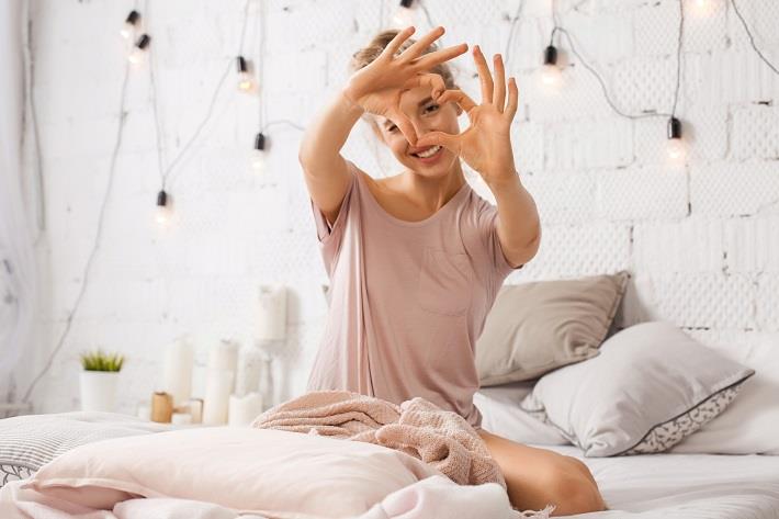 אישה מסמלת לב עם הידיים, כסימן לאהבה עצמית 