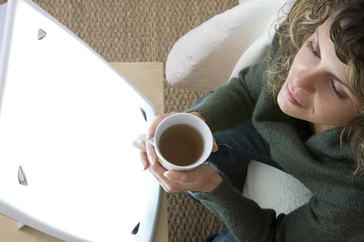 אישה יושבת מול מסך אור כחלק מטיפול באור