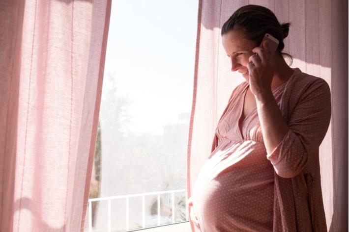 אישה בשבוע 39 להריון מחויכת, נראית רגועה ומשוחחת בטלפון