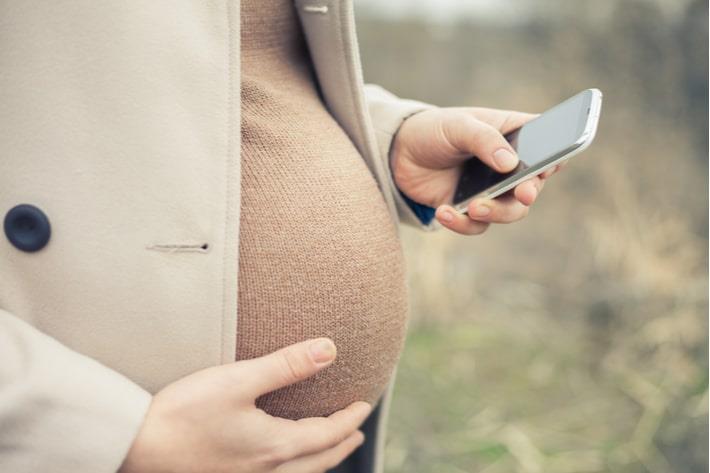 אישה בשבוע 38 להריון מחזיקה טלפון נייד ביד
