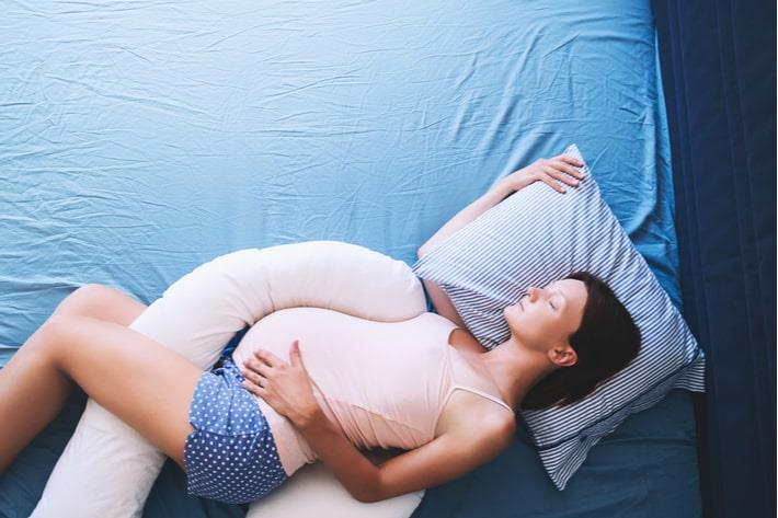 אישה בשבוע 29 להריון שוכבת עם כרית בין הרגליים