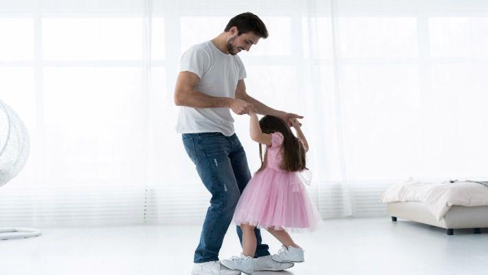 אבא רוקד עם ילדה קטנה בסלון