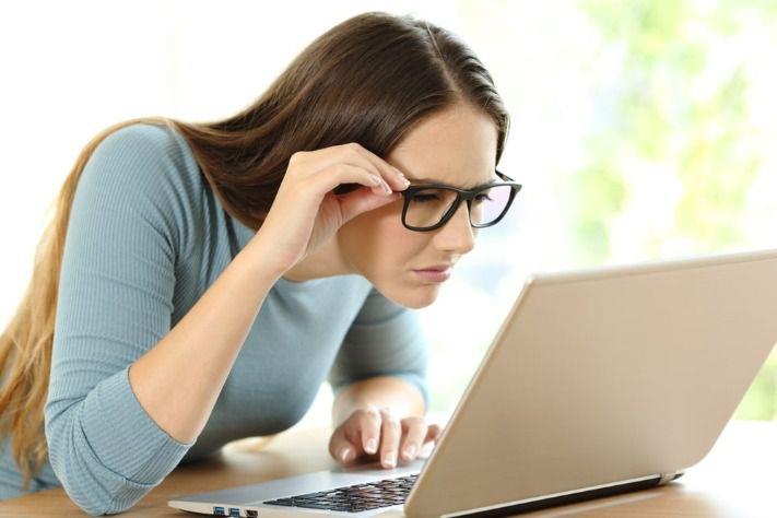 אישה שמרכיבה משקפיים סובלת מהיפראופיה, רוחק ראיה, המקשה עליה לראות את הכתוב על צג המחשב 
