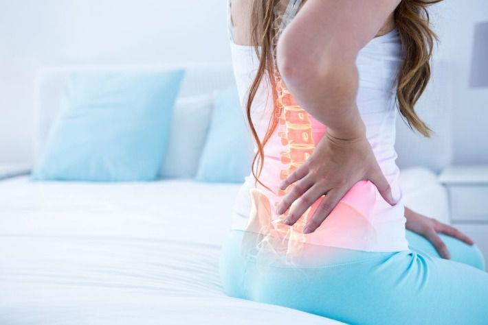 אישה סובלת מכאבי גב בשל פריצת דיסק