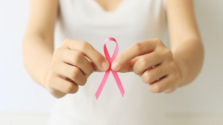 אישה צעירה מחזיקה סרט ורוד המסמל מודעות לסרטן השד