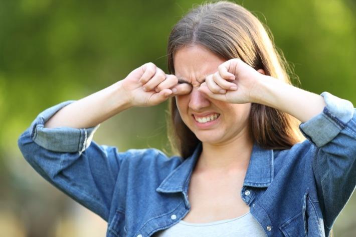 בחורה צעירה סובלת מגירוי וגרד בעיניים בעקבות דלקת עיניים אלרגית 