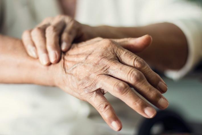 אדם מבוגר מחזיק את ידו כי סובל מרעד בשל מחלת פרקינסון