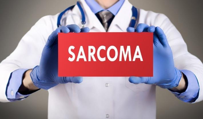 אילוסטרציה רופא מחזיק שלט עליו כתוב סרקומה- סרטן המתפתח ברקמות הרכות