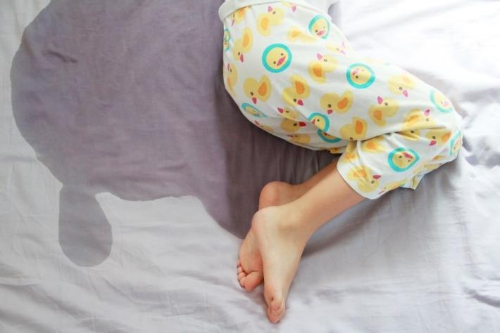 אילוסטרציה: ילד שוכב על המיטה וסובל מהרטבת לילה 