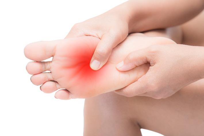 אישה סובלת מכאבים בכפות הרגליים הנובעים מנוירופתיה