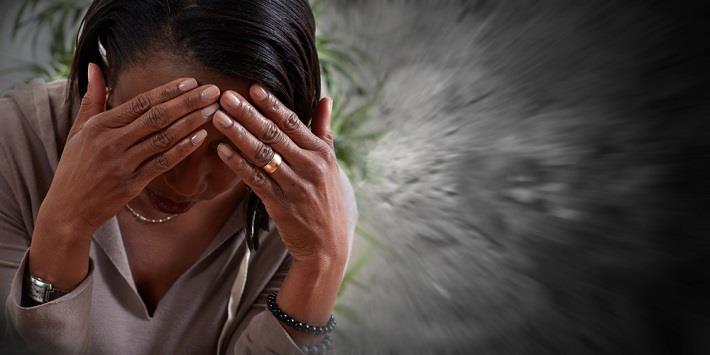 אישה צעירה מחזיקה את ראשה במטרה להקל על כאב הראש כתוצאה ממיגרנה