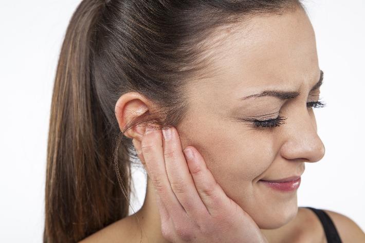 אישה סובלת מכאבי אוזניים בשל דלקת כרונית באוזן התיכונה