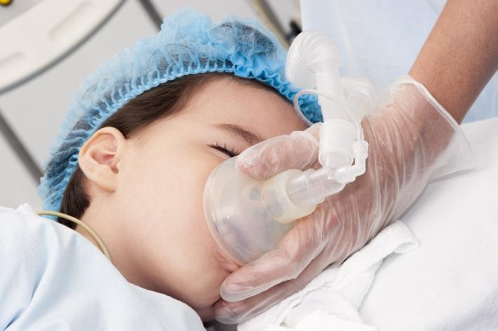 רופא משתמש במסכה לצורך ביצוע הרדמה כללית לילד לפני ניתוח