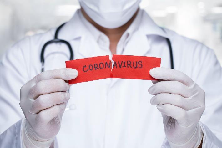 אילוסטרציה: רופא עם מסכה וכפפות מחזיק שלט עליו כתוב קורונה