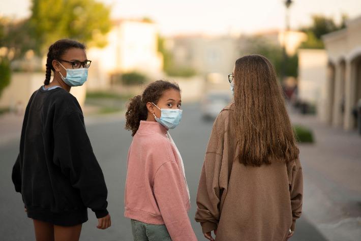 שלוש נערות משתמשות במסכות כירורגיות כדי להגן מפני הדבקה וירוס קורונה 