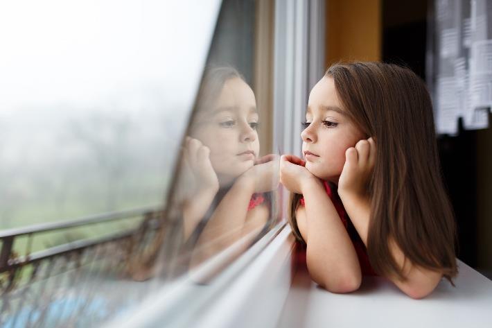 ילדה מסתכלת מעבר לחלון בשעמום בימי הסגר 