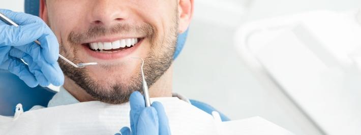 גבר צעיר מחייך לאחר טיפול שיניים אסתטי להדבקת ציפויים על גבי השיניים