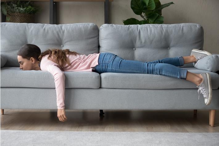 אישה צעירה דוחה משימות ושוכבת על הספה 
