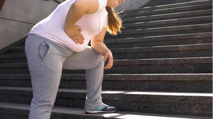 אישה מתקשה לעלות במדרגות בגלל שסובלת מהשמנה 