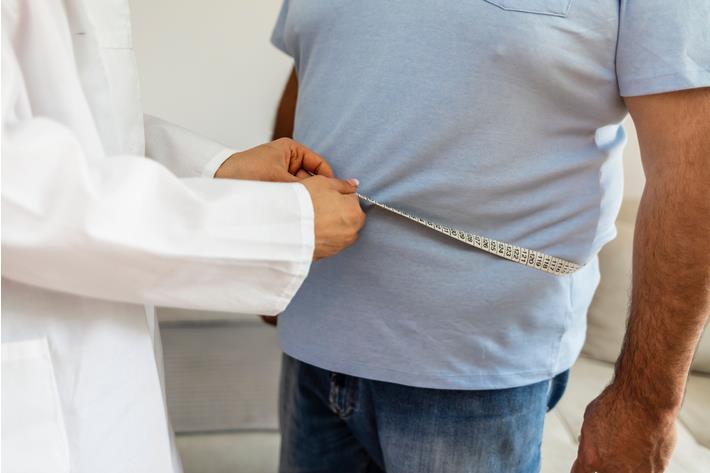 רופאה מודדת למטופל היקף מותניים כחלק מתהליך הבירור לפני תחילת הטיפול התרופתי בהשמנה