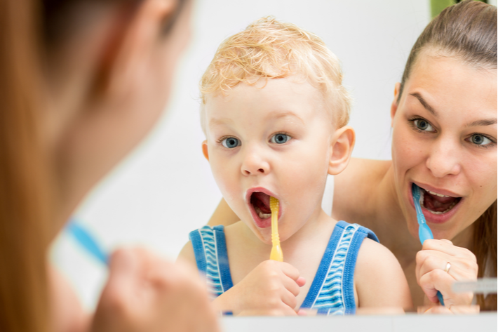 אמא וילד קטן מצחצחים שיניים לראשונה עם בקיעת השיניים