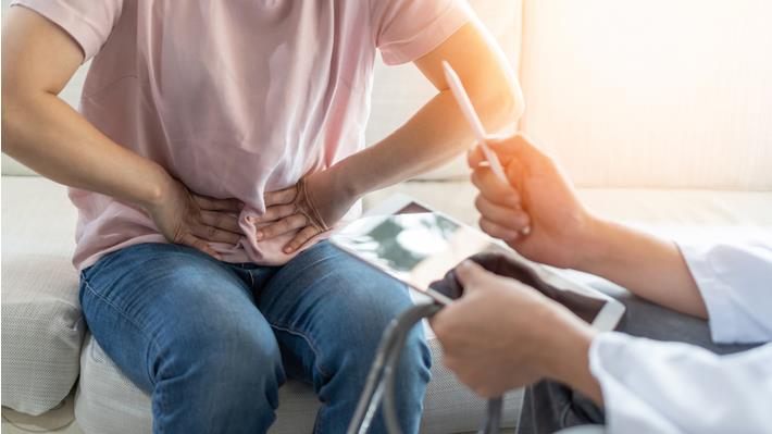 גבר סובל מכאבים בבטן התחתונה בפגישה אצל רופא מחשד לגידול קיבה 