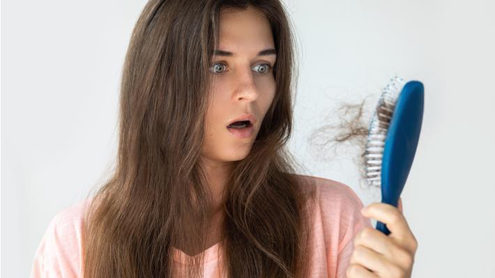 אישה צעירה סובלת מנשירת שיער מוגברת כתוצאה מבעיות במערכת העיכול