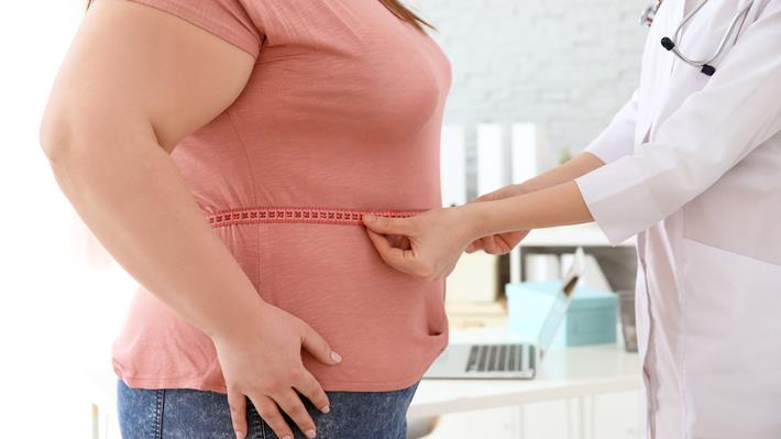 רופאה מודדת היקף מותניים של אישה הסובלת מהשמנה לקראת תכנון טיפול רב מערכתי בהשמנה