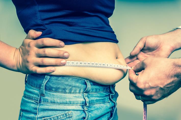 רופא מודד היקף מותניים כדי לאבחן השמנה בטנית - אחד מהמרכיבים המרכזיים של התסמונת המטבולית 