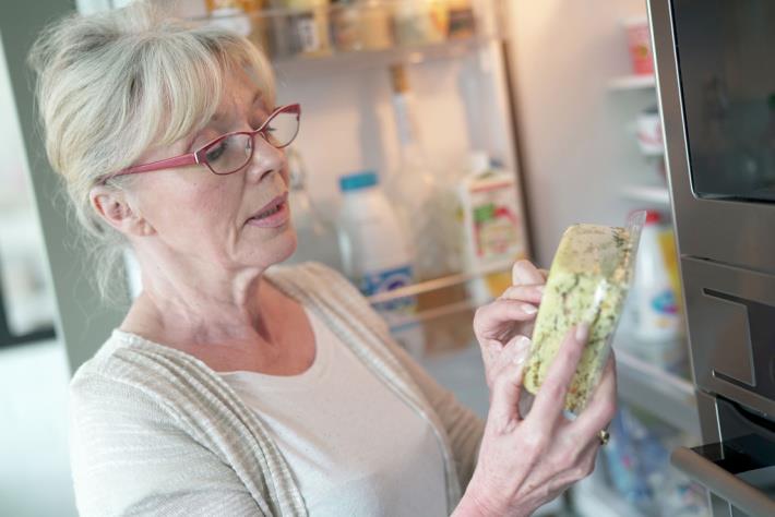 אישה בודקת תוקף של מוצר במקרר