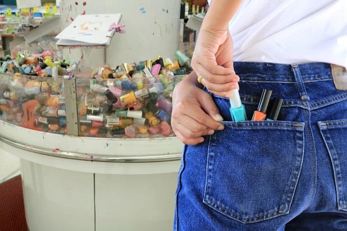 בחורה הסובלת מקלפטומניה מכניסה לק לכיסה בחנות