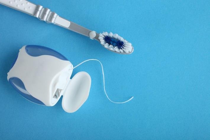חוט דנטלי ומברשת שיניים על רקע כחול