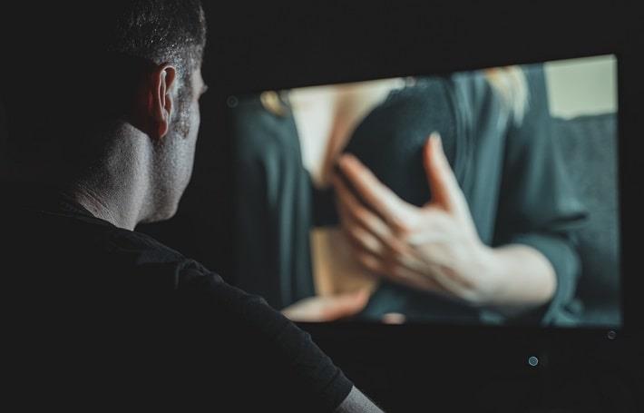 גבר שסובל מהתמכרות למין יושב מול מחשב וצופה בסרט ארוטי בשעת לילה מאוחרת