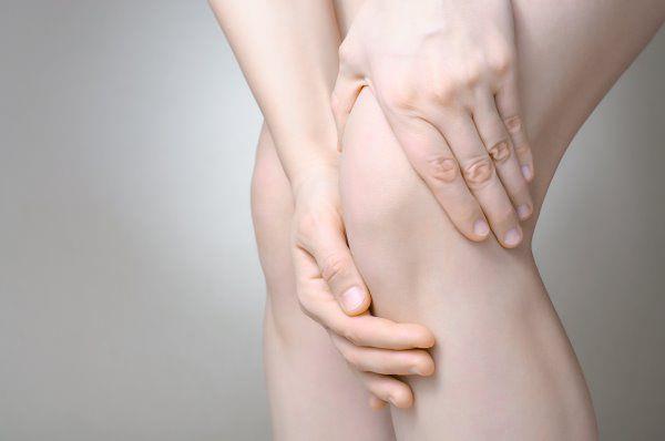 יד של אישה אוחזת בברך כואבת בגלל קרע במיניסקוס