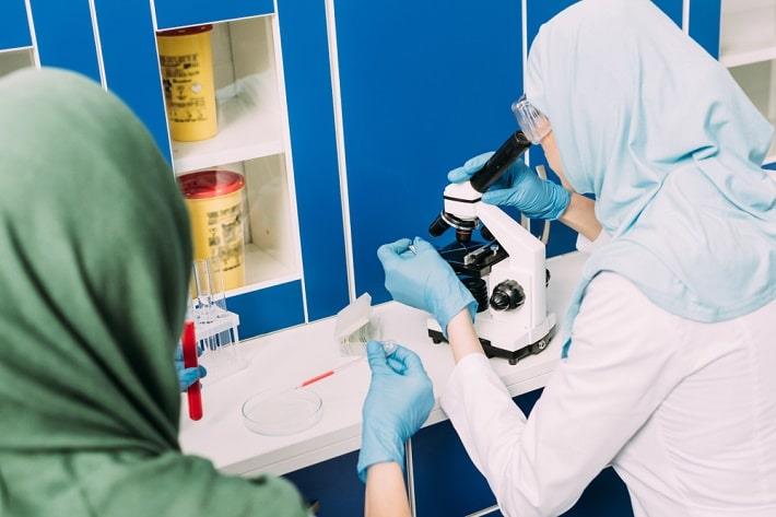אישה בודקת במיקרוסקופ דגימה של בדיקת מטאנפרינים בדם