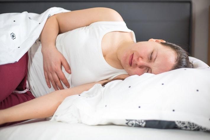 אישה עם קרוהן שוכבת וסובלת מכאבי בטן, בדיקת נוגדנים מסוג ASCA  