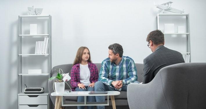 מתבגרת ואביה יושבים מול פסיכולוג במסגרת טיפול רגשי לילדים