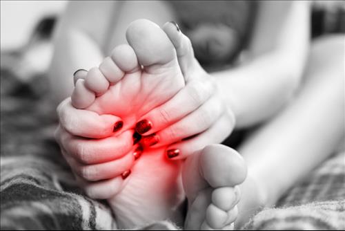 אישה נוגעת בכף רגל עם כאב, פודיאטריה